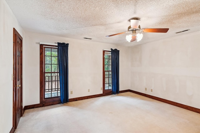 empty room featuring ceiling fan, light carpet, and a textured ceiling