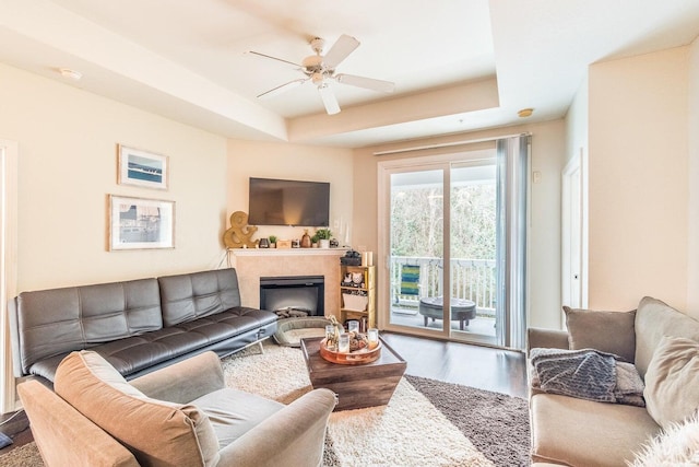 living room featuring hardwood / wood-style flooring, ceiling fan, and a raised ceiling