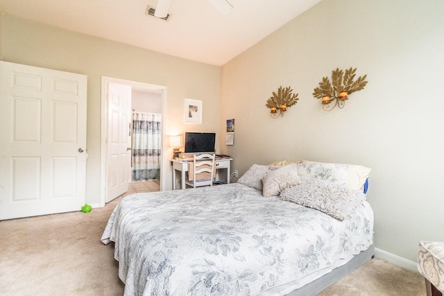 carpeted bedroom with ensuite bathroom, ceiling fan, and vaulted ceiling