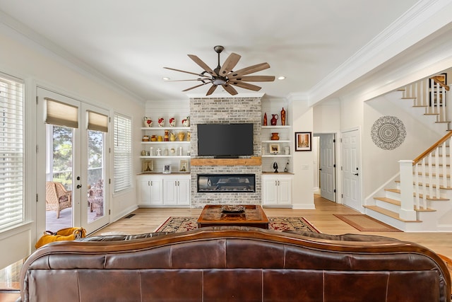 living area featuring crown molding, light wood finished floors, a ceiling fan, and stairs