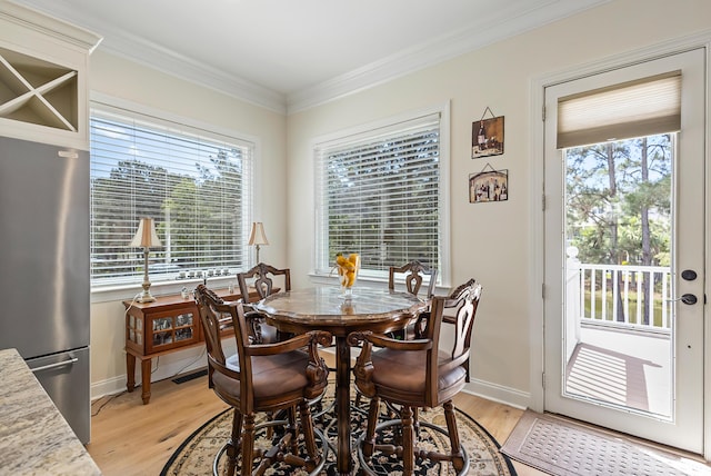 dining room with light wood-style floors, baseboards, and crown molding