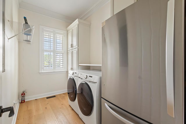 clothes washing area with crown molding, cabinet space, light wood finished floors, visible vents, and washer and clothes dryer