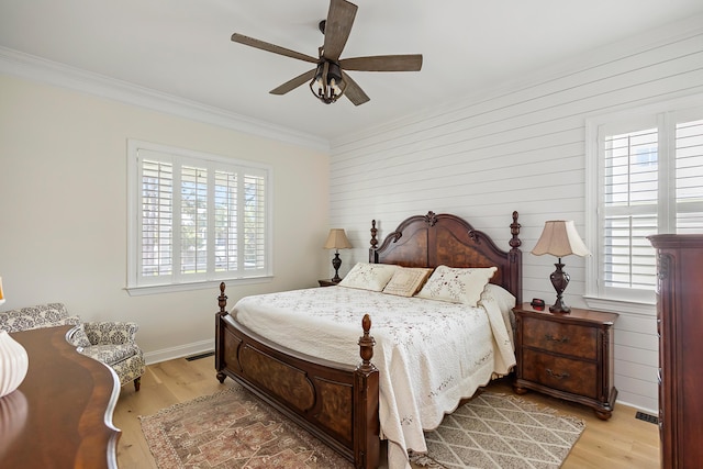 bedroom featuring light wood-style floors, crown molding, and multiple windows