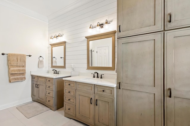 full bathroom with crown molding, two vanities, a sink, baseboards, and tile patterned floors
