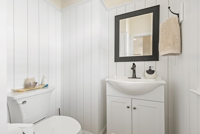 half bath with vanity, a decorative wall, and toilet