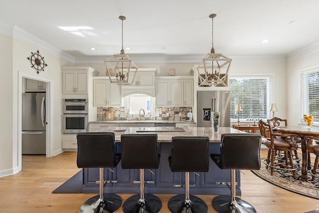kitchen with backsplash, appliances with stainless steel finishes, a center island, a sink, and light wood finished floors