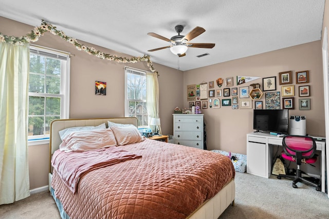 bedroom featuring light carpet, ceiling fan, and a textured ceiling