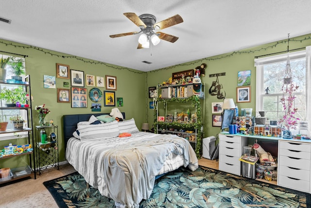 bedroom featuring ceiling fan, light carpet, and a textured ceiling