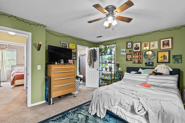 carpeted bedroom with ceiling fan, ensuite bath, and a textured ceiling