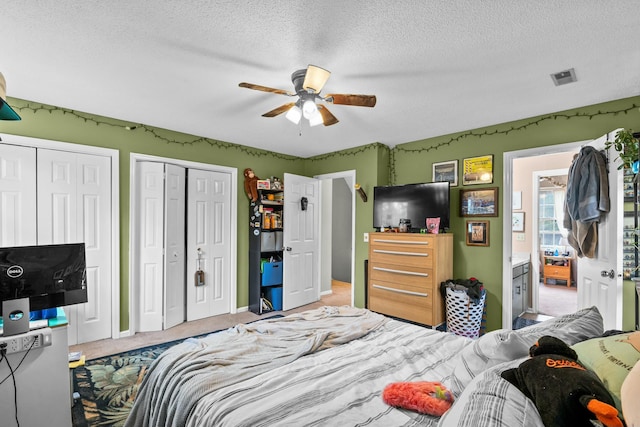 carpeted bedroom with multiple closets, ceiling fan, and a textured ceiling