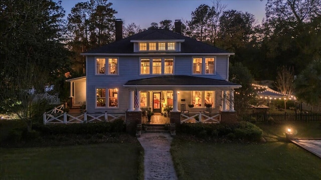 back house at dusk featuring a porch