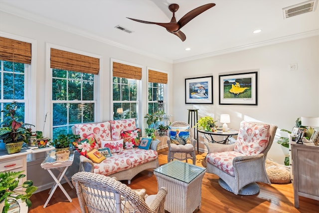 living room featuring light hardwood / wood-style floors, ceiling fan, and crown molding