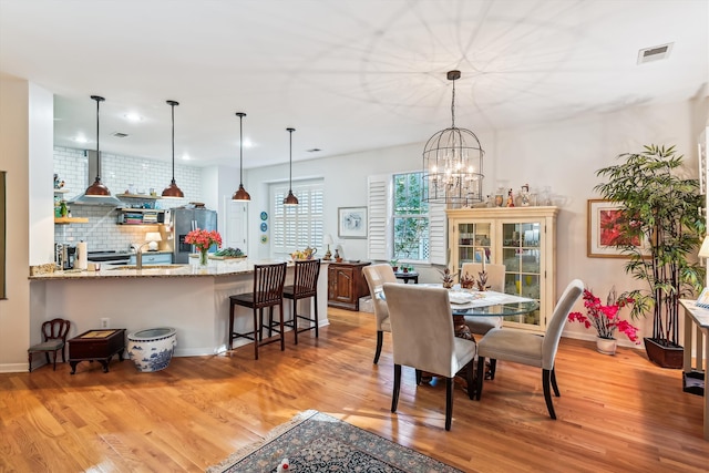 dining space featuring sink, a notable chandelier, and light wood-type flooring