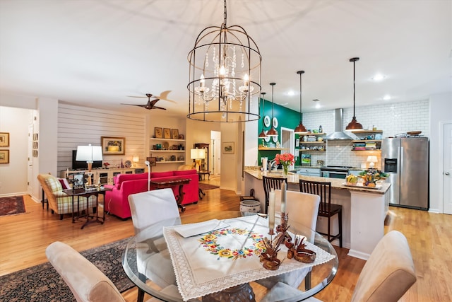 dining area with wood-type flooring and ceiling fan with notable chandelier