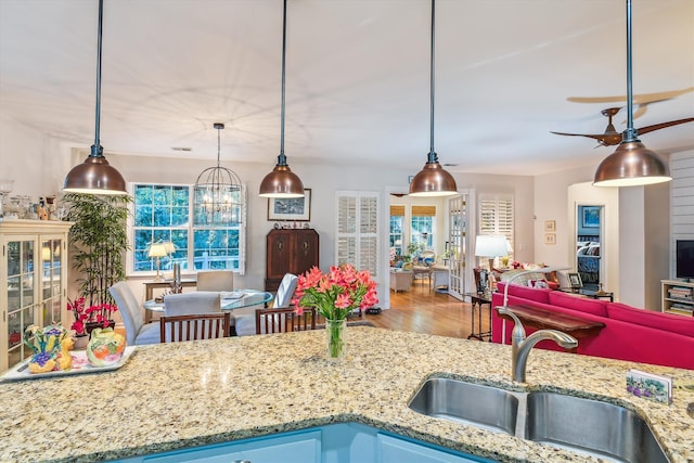 kitchen with wood-type flooring, a wealth of natural light, hanging light fixtures, and sink