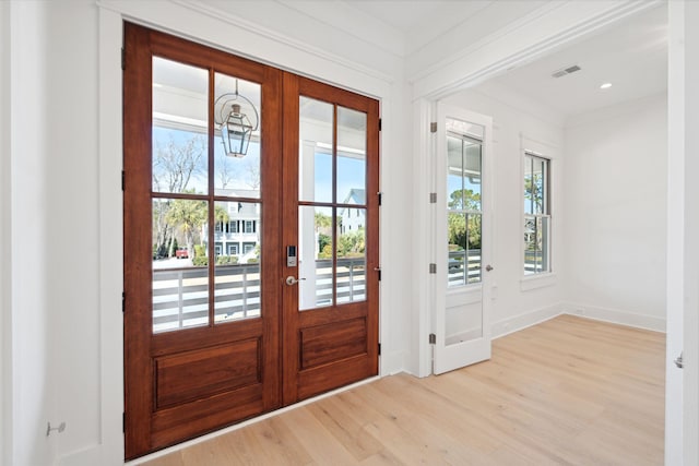 doorway to outside with crown molding, french doors, a healthy amount of sunlight, and light wood-type flooring