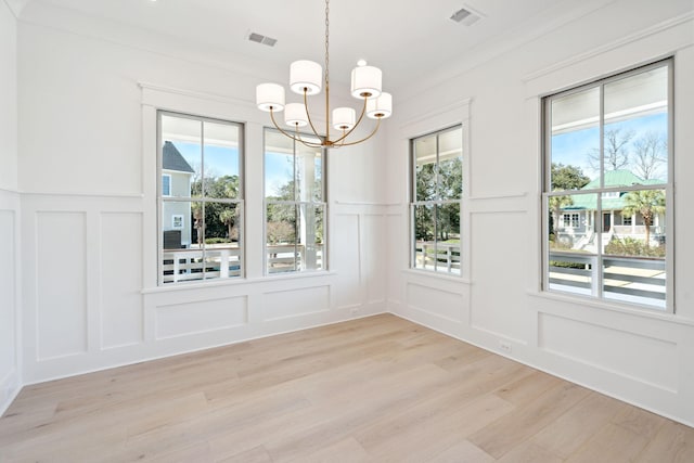 unfurnished dining area featuring an inviting chandelier and light wood-type flooring