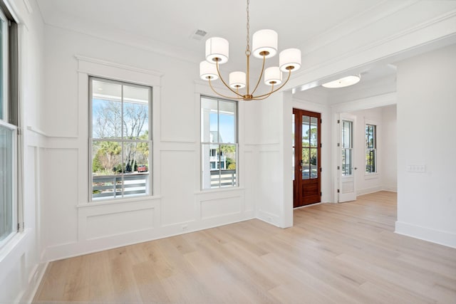 interior space with ornamental molding, an inviting chandelier, and light wood-type flooring