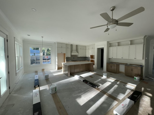 kitchen featuring a spacious island, white cabinets, pendant lighting, and wall chimney range hood