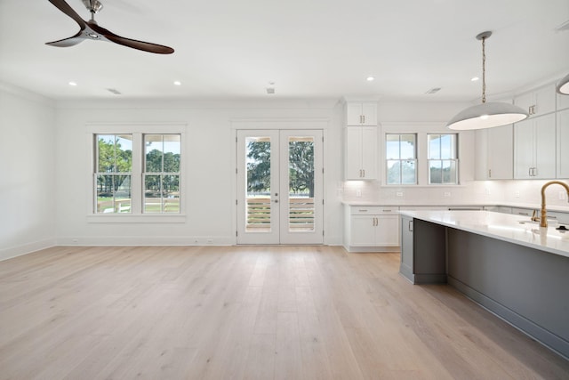 kitchen with white cabinetry, decorative light fixtures, light hardwood / wood-style floors, and backsplash