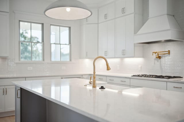 kitchen with sink, white cabinetry, light stone countertops, custom range hood, and stainless steel gas stovetop