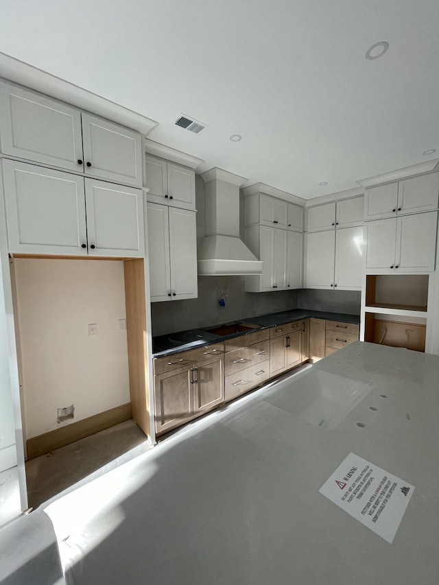 kitchen featuring white cabinets, stovetop, and wall chimney exhaust hood