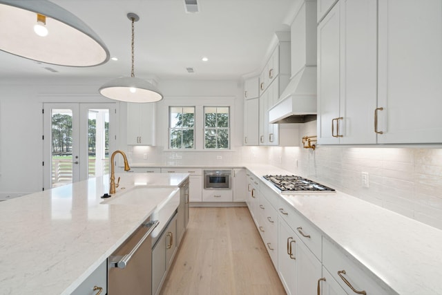 kitchen featuring decorative light fixtures, white cabinetry, custom exhaust hood, light stone counters, and stainless steel appliances