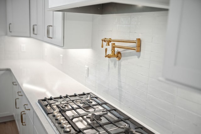 kitchen featuring stainless steel gas stovetop, decorative backsplash, and tile walls