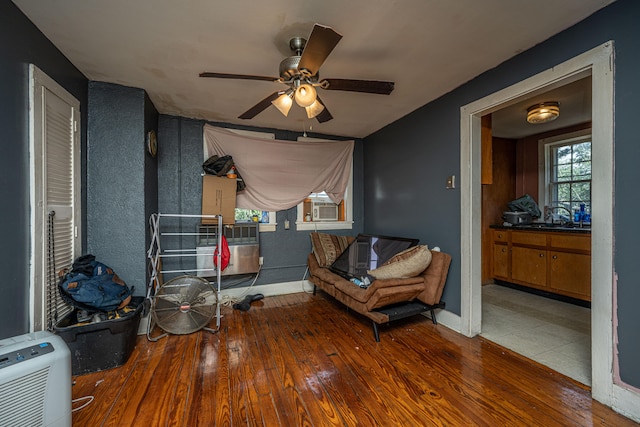 living area featuring wood-type flooring, cooling unit, and ceiling fan