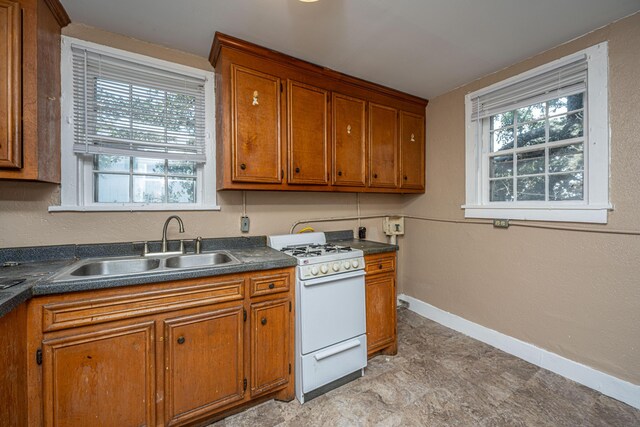 113 America St Unit A, B, C, D, Charleston, SC 29403 - kitchen featuring white gas range, brown cabinetry, a sink, baseboards, and dark countertops