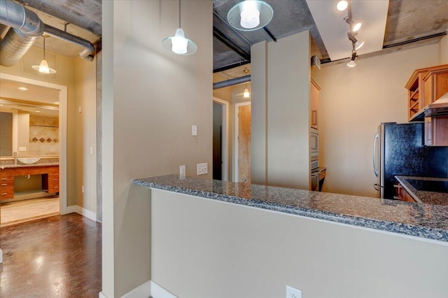 kitchen featuring dark stone counters, stainless steel appliances, decorative light fixtures, and track lighting