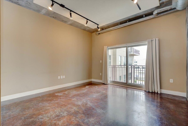 spare room with rail lighting and concrete floors