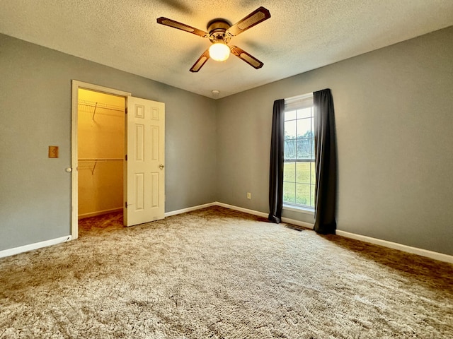 carpeted spare room with a textured ceiling and ceiling fan