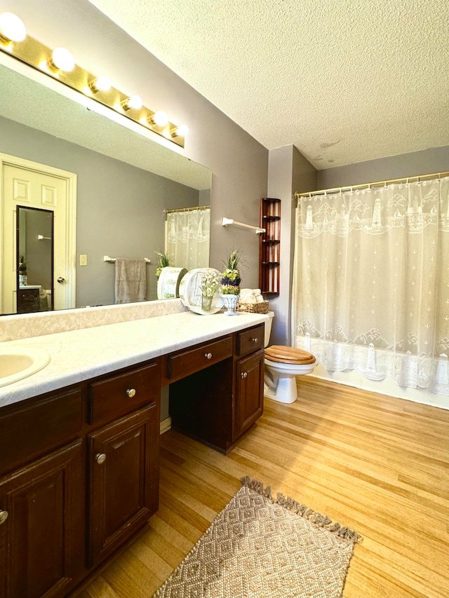 bathroom featuring vanity, wood-type flooring, a textured ceiling, and toilet