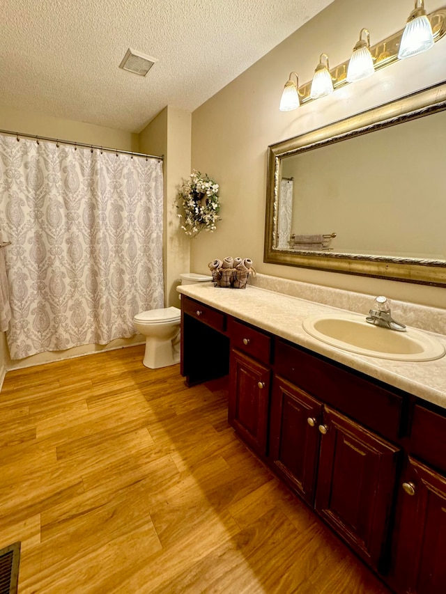 bathroom with vanity, a textured ceiling, hardwood / wood-style flooring, and toilet