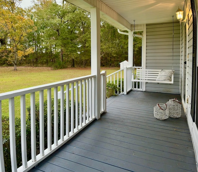 wooden terrace featuring a lawn and covered porch