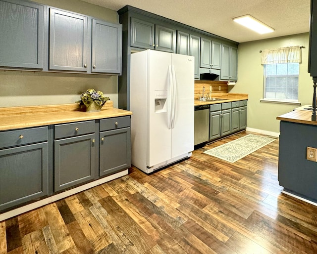 kitchen with dishwasher, sink, dark hardwood / wood-style floors, white fridge with ice dispenser, and a textured ceiling