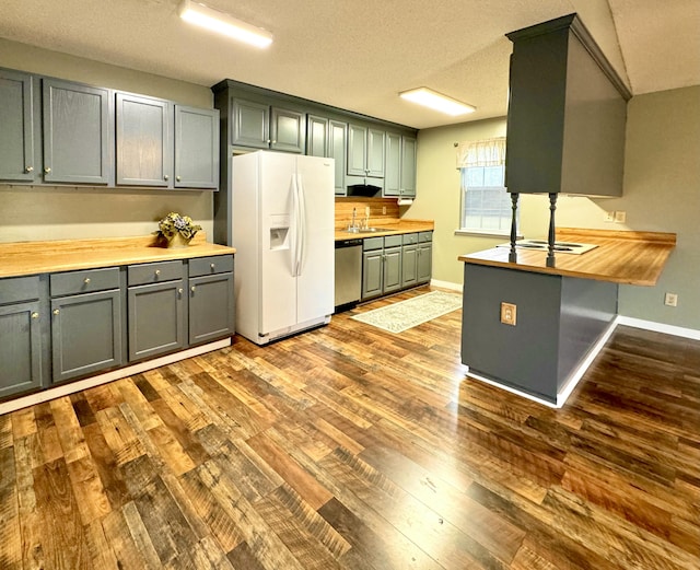 kitchen featuring wood counters, a textured ceiling, white refrigerator with ice dispenser, hardwood / wood-style flooring, and dishwasher