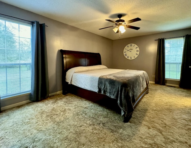 bedroom featuring light carpet, a textured ceiling, and ceiling fan