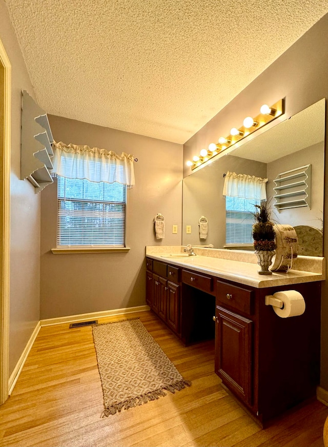 bathroom featuring vanity, wood-type flooring, and a textured ceiling