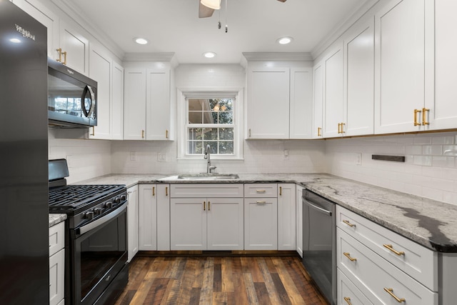 kitchen with stainless steel appliances, white cabinetry, sink, and light stone counters