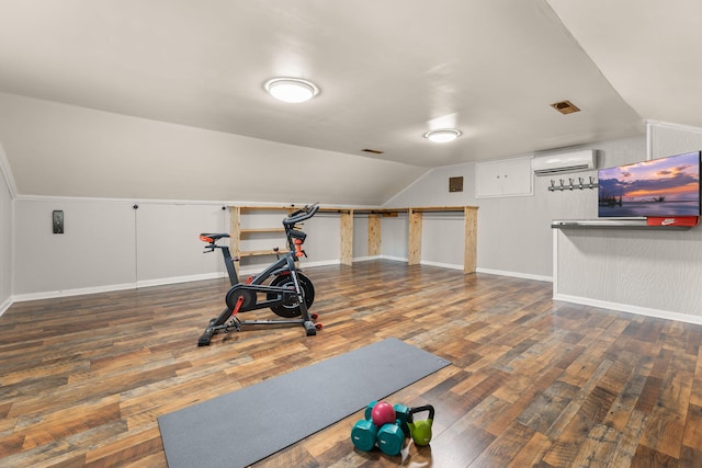 exercise area with vaulted ceiling, a wall mounted air conditioner, and dark hardwood / wood-style flooring