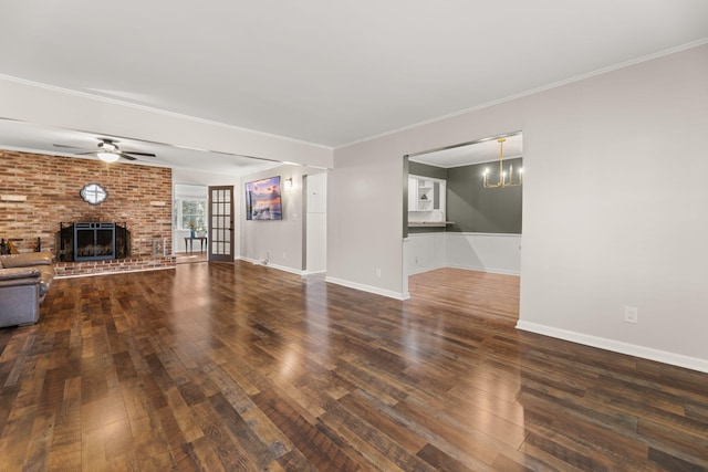 unfurnished living room with a fireplace, crown molding, dark wood-type flooring, and ceiling fan with notable chandelier