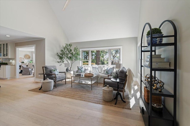 living area with baseboards, high vaulted ceiling, and light wood-style floors