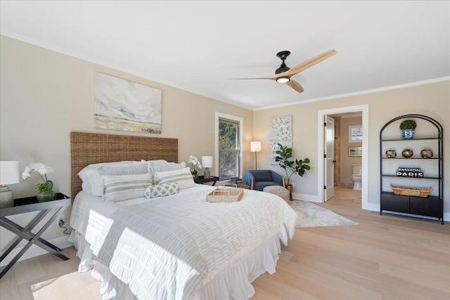 bedroom featuring ceiling fan, baseboards, ornamental molding, light wood-style flooring, and ensuite bath