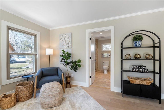 sitting room featuring plenty of natural light, light wood-style floors, baseboards, and ornamental molding