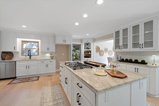 kitchen with a sink, white cabinets, light stone counters, and stainless steel appliances