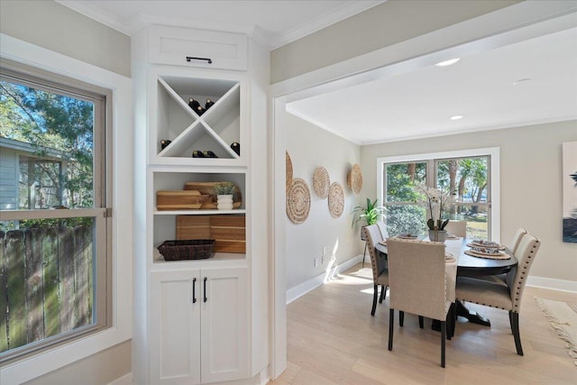 dining area with light wood-style flooring, built in shelves, crown molding, and baseboards