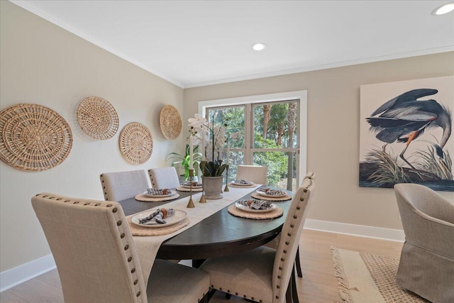 dining area featuring baseboards, crown molding, and light wood finished floors