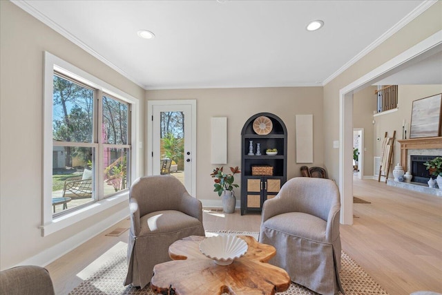 sitting room featuring light wood-style flooring, baseboards, a fireplace, and crown molding